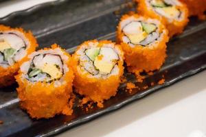 California maki sushi roll on black plate, japanese food photo