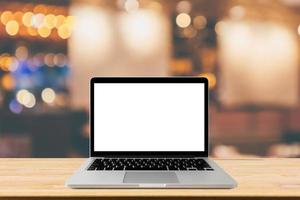 Blank screen laptop computer on wood table top with blur cafe restaurant with abstract bokeh light defocused background photo