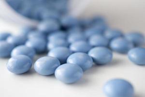 Píldoras de medicina azul con botella sobre fondo blanco. foto