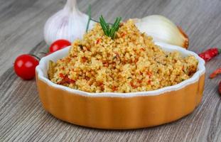 Couscous in a bowl on wooden background photo