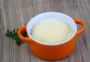 Shredded parmesan in a bowl on wooden background photo