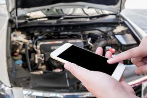 woman using mobile phone with broken down car photo