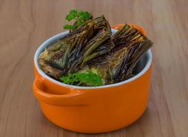 Grilled artishokes in a bowl on wooden background photo