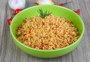 Couscous in a bowl on wooden background photo