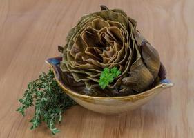 Boiled artichokes in a bowl on wooden background photo