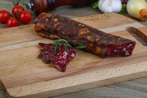 Salami sausage on wooden board and wooden background photo