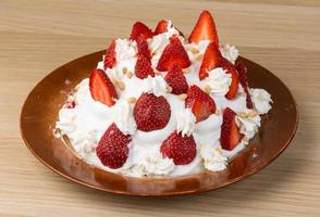 Strawberry cake on the plate and wooden background photo