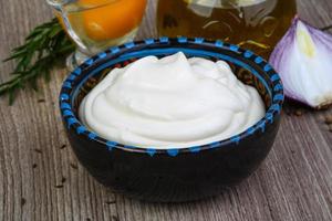 Mayonnaise sauce in a bowl on wooden background photo