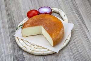 Suluguni cheese on wooden board and wooden background photo