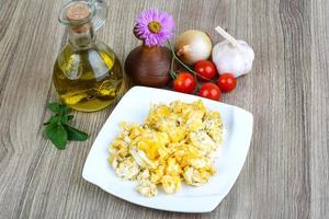 Scrambled eggs on the plate and wooden background photo