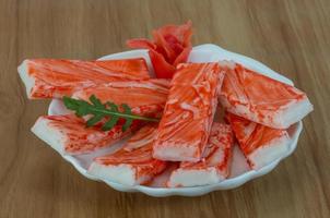 Crab sticks on the plate and wooden background photo