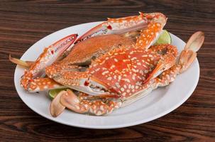 Boiled crabs on the plate and wooden background photo