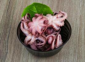 Marinated octopus in a bowl on wooden background photo