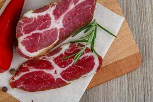 Smoked bacon on wooden board and wooden background photo