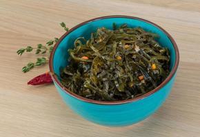 Laminaria salad in a bowl on wooden background photo