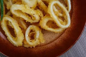 Squid rings on the plate and wooden background photo