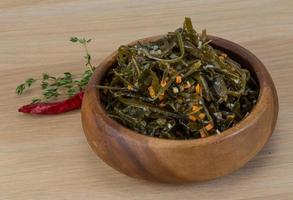 Laminaria salad in a bowl on wooden background photo