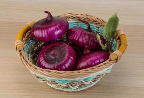 Violet onion in a basket on wooden background photo