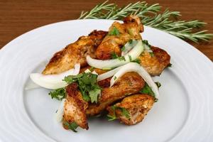 Chicken wings on the plate and wooden background photo