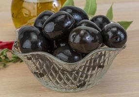 Black olives in a bowl on wooden background photo