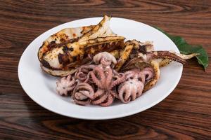 Boiled octopus on the plate and wooden background photo