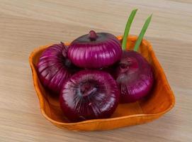 Violet onion in a bowl on wooden background photo