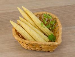 Baby corn in a basket on wooden background photo