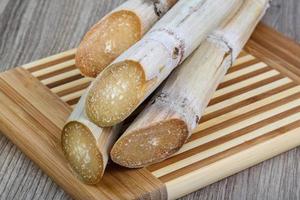 palitos de azúcar en tablero de madera y fondo de madera foto