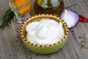 Mayonnaise sauce in a bowl on wooden background photo