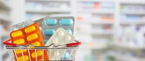 Medicine pill tablet in shopping basket with pharmacy drugstore shelves blurred background photo