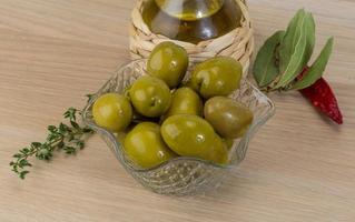 Green olives in a bowl on wooden background photo