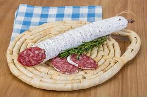 Fuet sausage on wooden board and wooden background photo