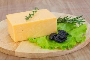 Yellow cheese on wooden board and wooden background photo