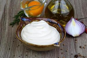 Mayonnaise sauce in a bowl on wooden background photo