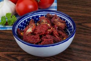 Dried tomtoes in a bowl on wooden background photo