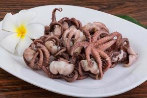 Boiled octopus on the plate and wooden background photo