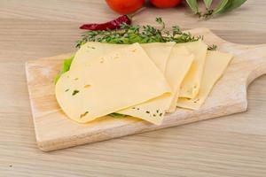 Sliced cheddar on wooden board and wooden background photo