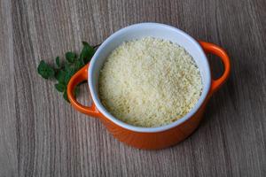 queso parmesano rallado en un recipiente sobre fondo de madera foto