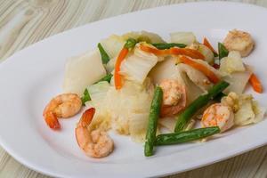 Shrimp salad on the plate and wooden background photo