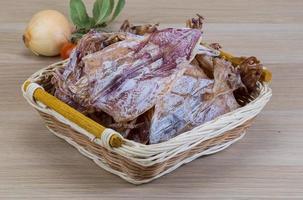 Dried squid in a basket on wooden background photo