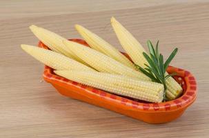 Baby corn in a bowl on wooden background photo