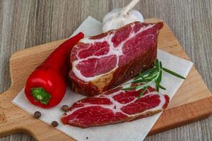 Smoked bacon on wooden board and wooden background photo