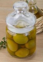 Green olives in a bowl on wooden background photo