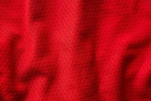 Red fabric sport clothing football jersey with air mesh texture background photo