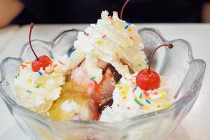 ice cream in glass bowl with whipped cream and red cherry on top photo