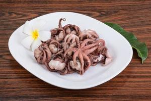 Boiled octopus on the plate and wooden background photo