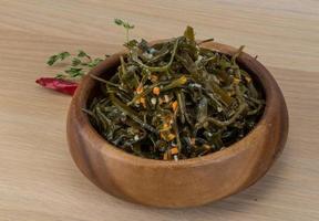 Laminaria salad in a bowl on wooden background photo