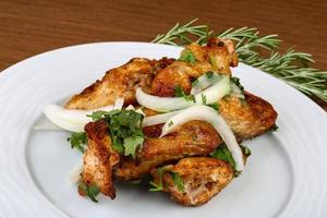 Chicken wings on the plate and wooden background photo