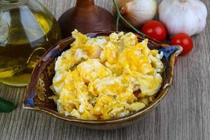 Scrambled eggs in a bowl on wooden background photo