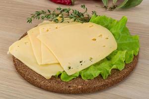 Sliced cheddar on wooden board and wooden background photo